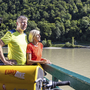 Zwei Radfahrer auf einer Fähre auf der Donau mit Fahrrädern im Vordergrund.