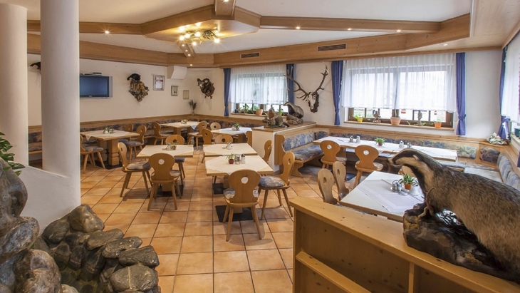 Gemütlicher Speisesaal mit Holzmöbeln und dekorativen Elementen an den Wänden.