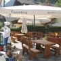 Terrasse eines Restaurants mit Holzmöbeln und großen Sonnenschirmen.