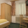 Einfach eingerichtetes Hotelzimmer mit Bett, Schreibtisch, Stuhl und Fernseher.