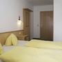 Hotelzimmer mit zwei Einzelbetten, hellem Holz und gelber Bettwäsche.