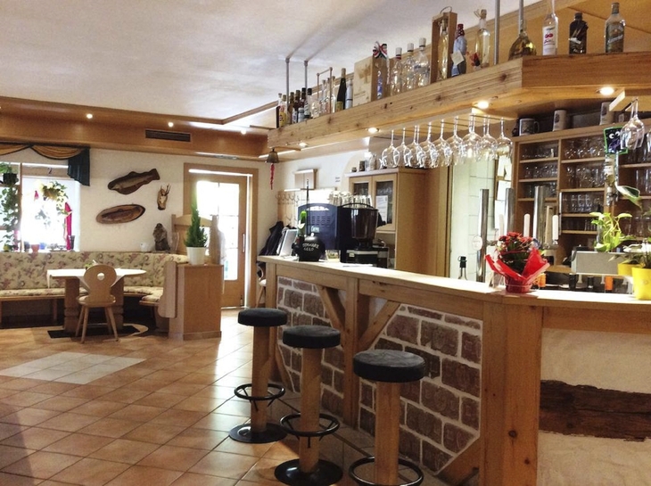 Innenansicht einer Hotelbar mit Tresen, Barhockern und gemütlicher Sitzgruppe.