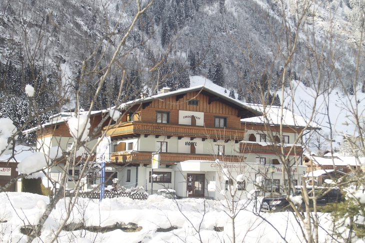 Ein von Schnee bedecktes Hotel im Winter in einer bergigen Landschaft.