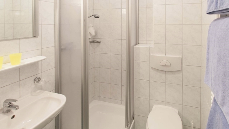 Helles Badezimmer mit Dusche, WC und Waschbecken.
