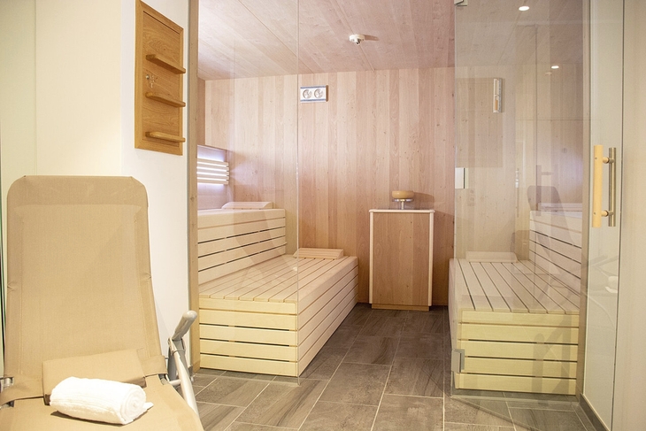 Saunabereich mit hölzernen Bänken und Glaswänden im Wellnessbereich eines Hotels.