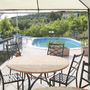 Terrasse mit Tisch und Stühlen vor einem Pool, umgeben von grüner Landschaft.