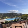 Terrasse mit Pool und Liegestühlen, Aussicht auf Hügel und blauen Himmel.