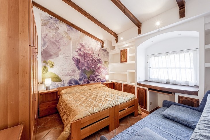 Helles Schlafzimmer mit Holzmöbeln und Blumendekoration an der Wand.