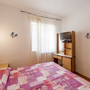 Schlafzimmer mit Doppelbett, TV und Fenster mit Vorhängen.