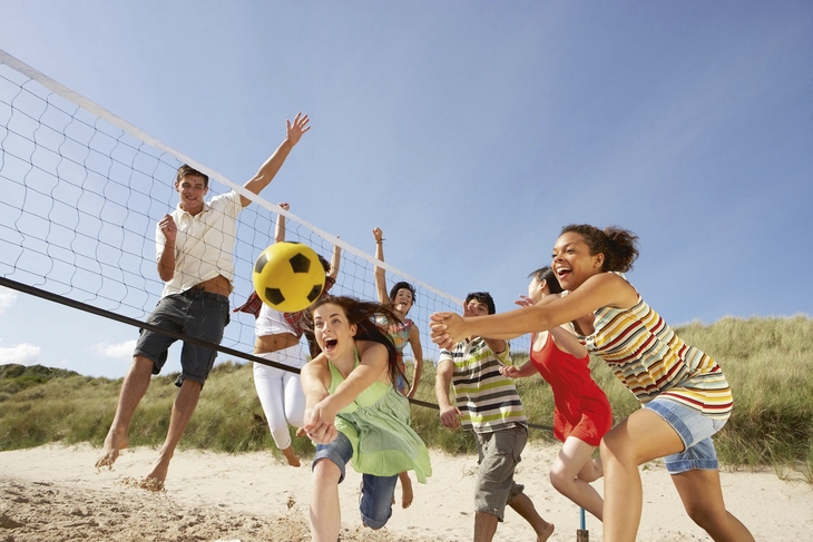 Menschen spielen Beachvolleyball am sonnigen Strand.