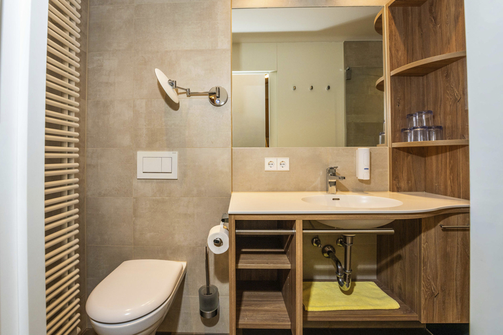 Modernes Badezimmer mit Waschbecken, Spiegel und Toilette.