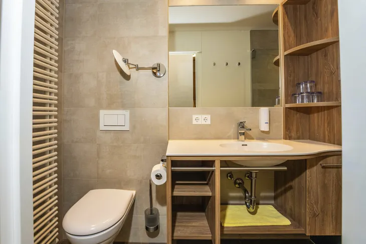 Modernes Badezimmer mit Waschbecken, Spiegel und Toilette.