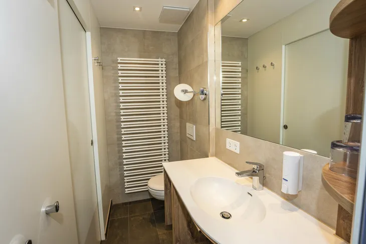 Modernes Badezimmer mit Waschbecken, Spiegel und Handtuchheizkörper.