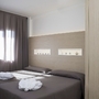 Helles Hotelzimmer mit zwei Einzelbetten und Vorhängen am Fenster.