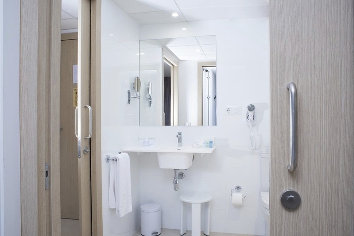Badezimmer in einem modernen Hotelzimmer mit Waschbecken, Spiegel und Handtuch.
