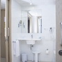Badezimmer in einem modernen Hotelzimmer mit Waschbecken, Spiegel und Handtuch.