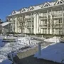 Mehrstöckiges Gebäude im Winter mit verschneitem Garten.