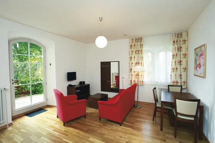Wohnzimmer mit roten Sesseln, Holzboden und großem Fenster.
