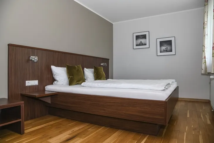 Holzgetäfeltes Schlafzimmer mit Doppelbett und zwei schwarz-weißen Bildern an der Wand.
