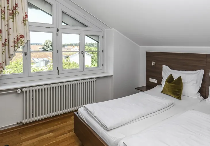 Schlafzimmer in Dachgeschoss mit Doppelbett und großem Fenster.
