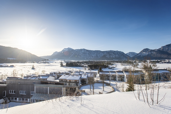 Winterliche Landschaft in Inzell mit verschneiten Gebäuden und Bergen im Hintergrund.
