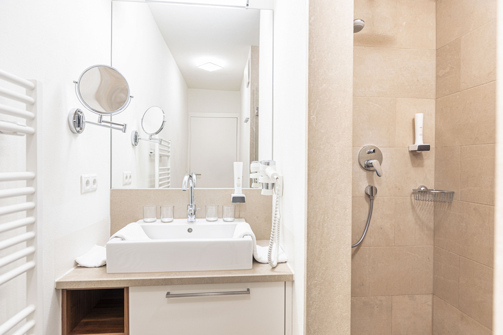 Badezimmer mit Waschbecken, Spiegel und Duschkabine.