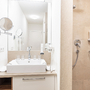 Badezimmer mit Waschbecken, Spiegel und Duschkabine.