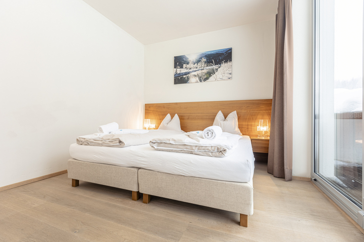 Helles Schlafzimmer mit Doppelbett, Holzfußboden und Bild an der Wand.
