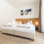 Helles Schlafzimmer mit Doppelbett, Holzfußboden und Bild an der Wand.