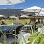 Pool mit Liegestühlen und Sonnenschirmen in bergiger Landschaft bei Radstadt.