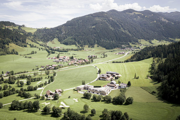 Landschaftspanorama mit Häusern und Bergen im Hintergrund.