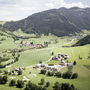 Landschaftspanorama mit Häusern und Bergen im Hintergrund.