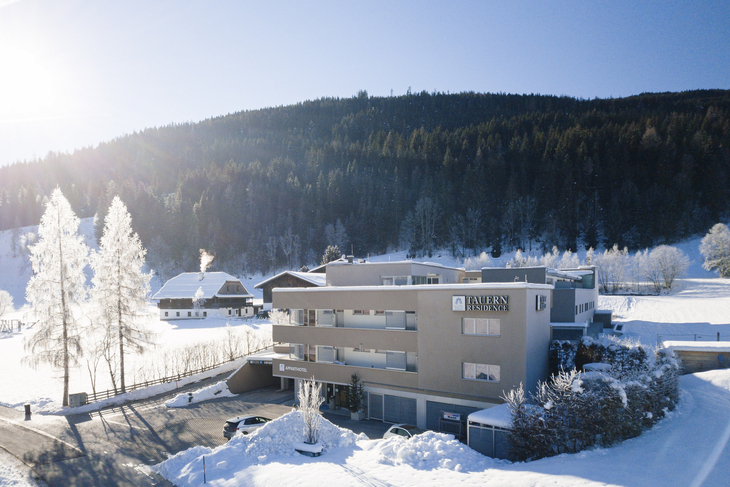Hotelgebäude im Winter vor bewaldeten Hügeln in Radstadt.