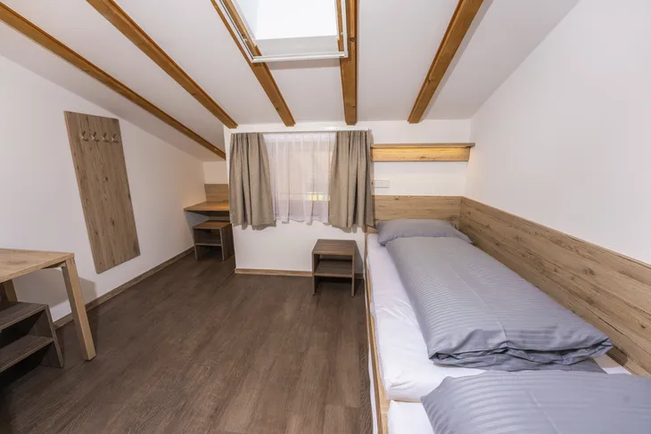 Helles Schlafzimmer mit zwei Einzelbetten, Holzverkleidung und Dachfenster.