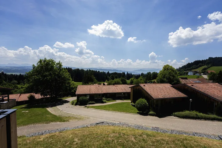 Dorflandschaft mit Häusern, Bäumen und bewölktem Himmel.