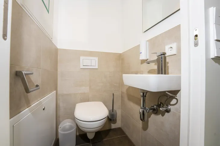 Kleines Badezimmer mit Toilette, Waschbecken und Handtuchhalter.