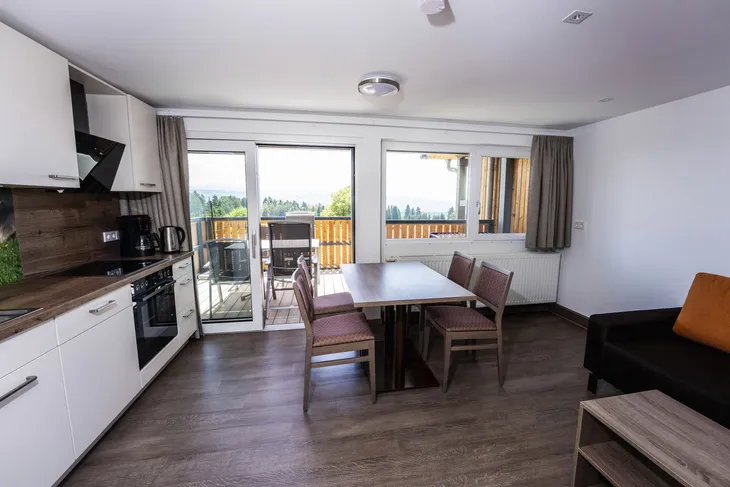 Moderne Küche und Essbereich mit Balkon und Ausblick.