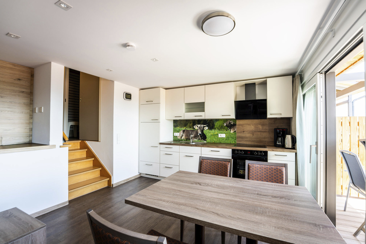 Moderne Küche mit Esstisch, Holzfußboden und Zugang zur Terrasse.