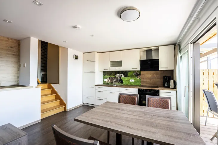 Moderne Küche mit Esstisch, Holzfußboden und Zugang zur Terrasse.