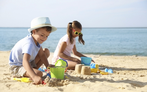 Kinder spielen am Strand im Sand vor dem Meer.