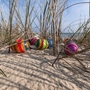 Bunte Ostereier in Sanddünen zwischen Grashalmen.