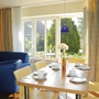 Wohnbereich mit Esstisch, blauen Sesseln und Blick auf Garten in Ferienanlage Harlesiel.