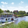 Bootsfahrt auf einem Fluss in Harlesiel, umgeben von grüner Landschaft.