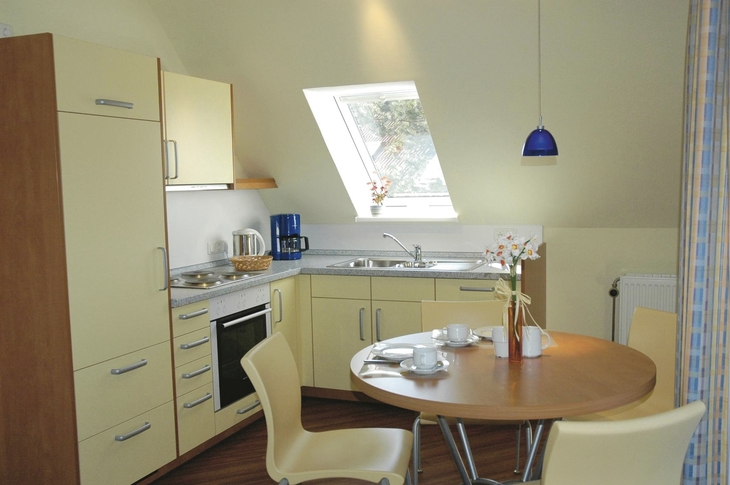 Moderne Küche mit Esstisch, Stühlen, Fenster und Beleuchtung in Ferienanlage Harlesiel.