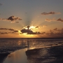 Sonnenuntergang mit Wolken und Lichtstrahlen über dem Wattenmeer mit breitem Priel.
