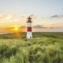 Leuchtturm und Haus auf einer Wiese bei Sonnenuntergang am Strand auf Sylt.