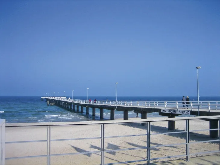 Steg am Timmendorfer Strand führt ins Meer bei klarem Himmel.