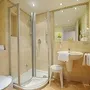 Modernes, helles Badezimmer mit Dusche, Waschbecken, Hocker, Handtüchern und WC, im Haus Oldenburg, in der Ferienanlage Timmendorfer Strand.