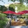 Außenbereich eines Cafés mit roten Sonnenschirmen und gelben Stühlen.