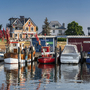 Boote im Hafen von Niendorf vor Gebäuden bei blauem Himmel und sonnigem Wetter.